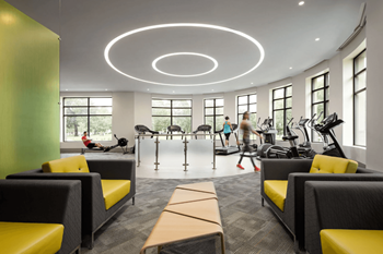 A gym with a variety of equipment and people working out.